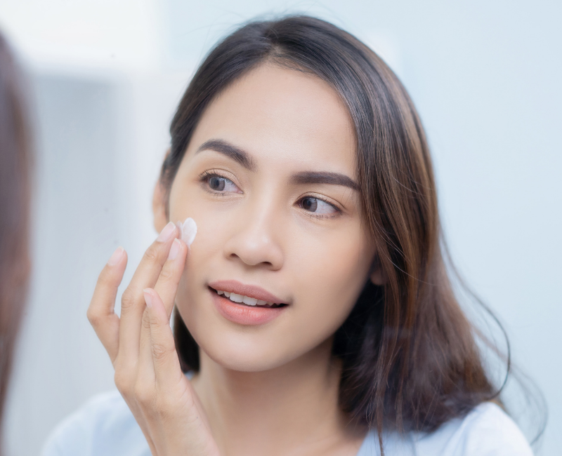 woman putting cream in front of glass