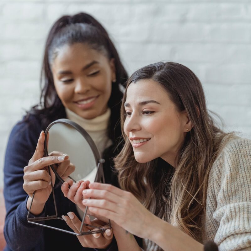 two girls white background looking at mirror